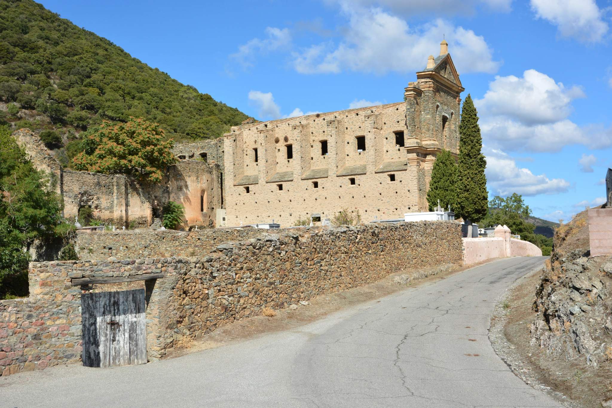 Village traditionnel de Corse avec une église au bord d'une route de montagne.