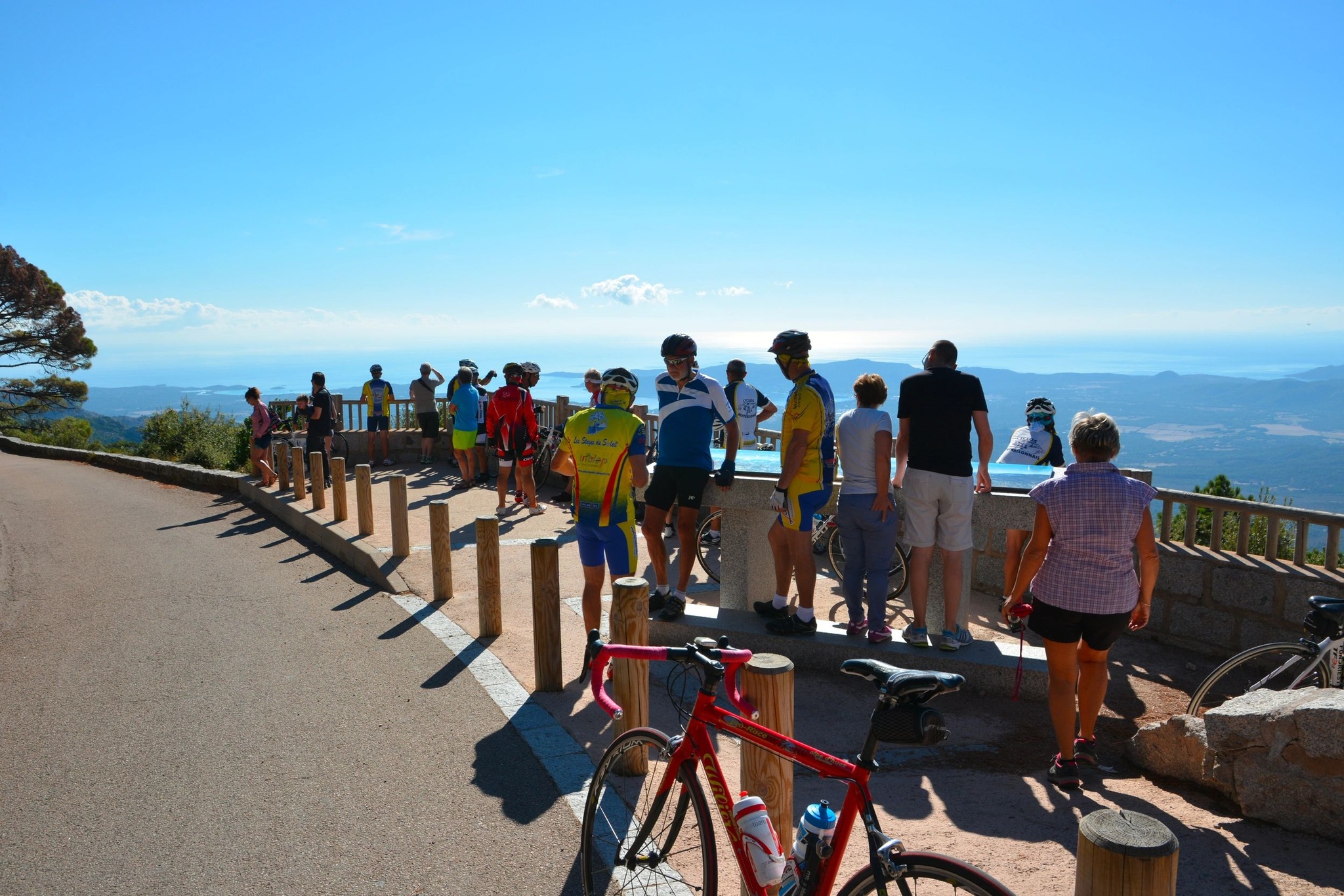Groupe de cyclistes en pause devant un panorama sur la mer en Corse.